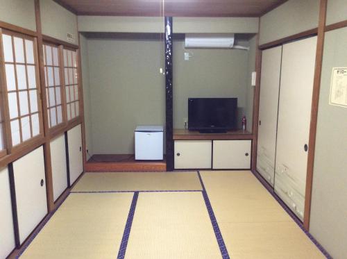 ein leeres Zimmer mit einem TV und einem Zimmer mit einem Zimmer in der Unterkunft Business Hotel Shizusato Ryokan in Ōgaki