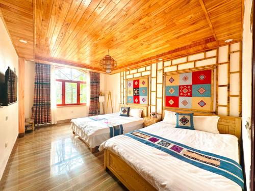 Dos camas en una habitación con techos de madera. en Ultra View Homestay, en Sa Pa