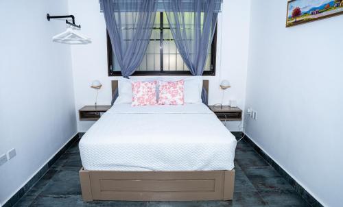 a bedroom with a bed and two windows at Hotelito Bonito Eli & Edw in Santo Domingo
