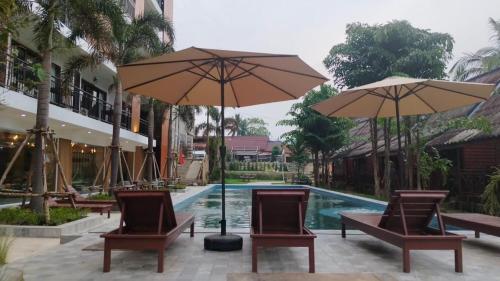 - une piscine avec des chaises et des parasols en face du complexe dans l'établissement Vang Vieng Bungalows, à Vang Vieng