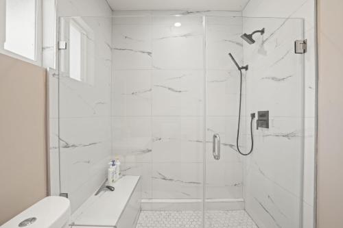 y baño blanco con ducha y aseo. en New Modern Cozy Guest House, Parking, Pet Friendly in Mar Vista! en Los Ángeles
