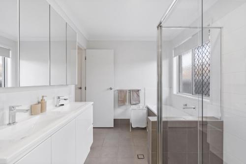- une salle de bains blanche avec deux lavabos et une douche dans l'établissement Tranquil Retreat Brisbane North, à North Lakes