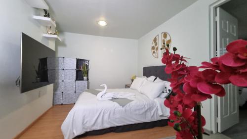 a bedroom with a bed with white sheets and red flowers at Departamento céntrico, amplio y nuevo cerca del Aeropuerto y GNP-Foro sol in Mexico City