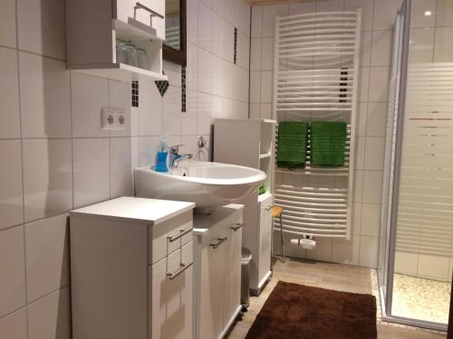 ein weißes Badezimmer mit einem Waschbecken und einem Spiegel in der Unterkunft Ferienwohnung Sandkaute in Hellstein
