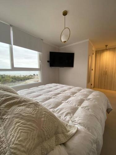 a white bed in a room with a window at Mar, bohemia y descanso in Coquimbo