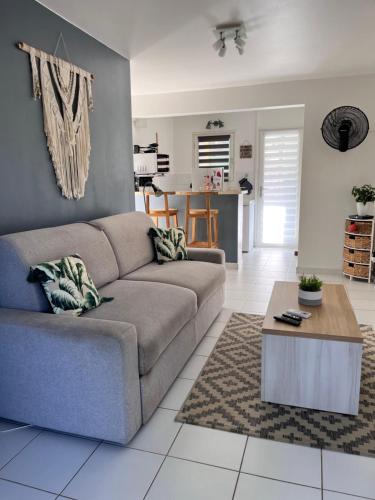 a living room with a couch and a table at Superbe studio de standing à 800m de la mer des Caraïbes le hameau de beauregard sainte anne in Sainte-Anne