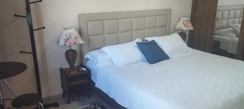 a bedroom with a large white bed with two lamps at Pousada da Paz in Curitiba