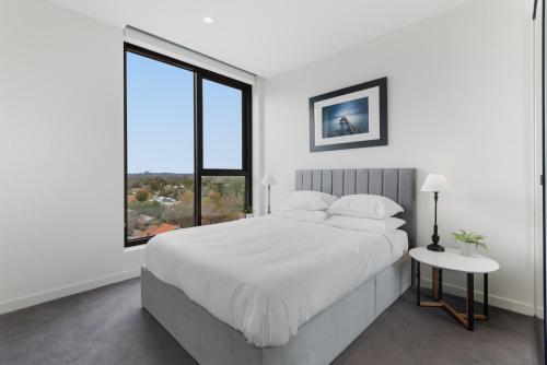 een witte slaapkamer met een groot bed en een raam bij Chic 2-Bed by Natural Trails with Pool & BBQ in Melbourne