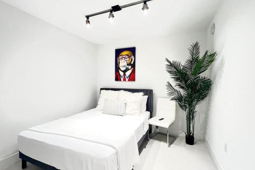 a white bedroom with a bed and a plant at 3 BR Masterpiece! Resort style Luxury! Prime Locale! in Miami