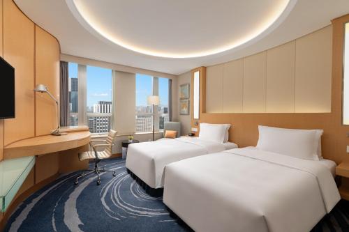 two beds in a hotel room with a large window at Crowne Plaza Shenzhen Futian, Near to Shenzhen Convention&Exhibition Centre, Shenzhen Stock Exchange and Shenzhen Civic Center, Outdoor Heated Pool in Shenzhen