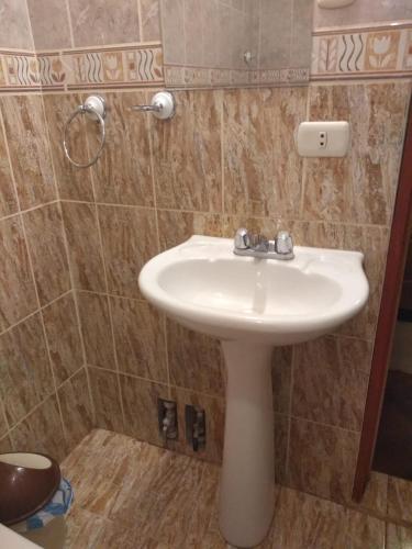 een badkamer met een witte wastafel en een douche bij PUNO EROPA HOTEL in Puno
