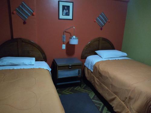 Habitación con 2 camas y mesa con lámpara. en PUNO EROPA HOTEL en Puno