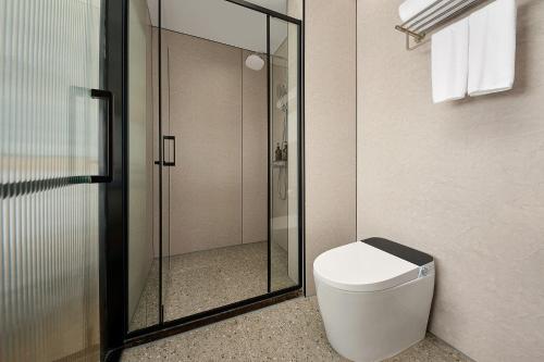 a bathroom with a toilet and a glass shower at 珠海海之珠丨Global Romantic Pearl酒店-拱北口岸珠海站店 in Zhuhai