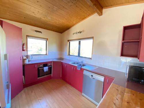 a kitchen with red cabinets and a sink at Pohara Tides - Poharas Beach Getaway in Pohara