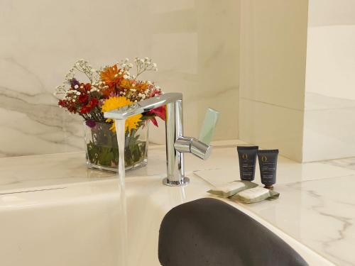 a bathroom sink with a faucet and a vase of flowers at FRATELLI CORP APART HOTEL in La Paz