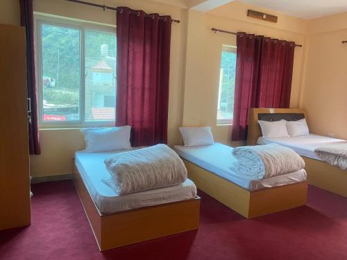 una camera con due letti e una finestra con tende rosse di Prashiddha Resort a Dakshīnkāli