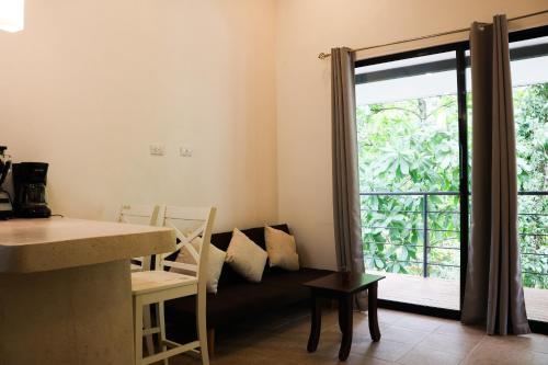 a living room with a couch and a large window at Vista Verde Surf & Studios - jungle View in Carmen