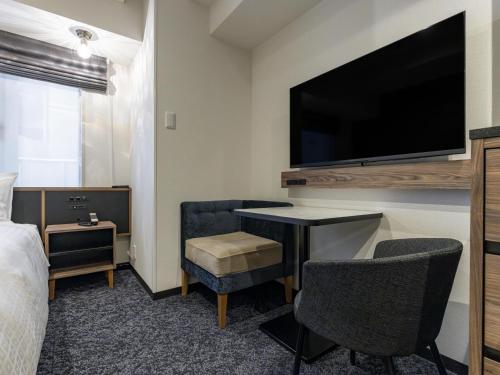 a hotel room with a bed and a flat screen tv at Tokyu Stay Nishi Shinjuku in Tokyo