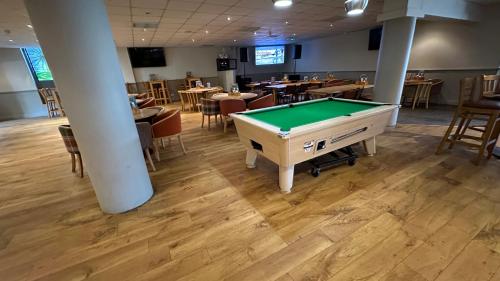 a pool table in a room with tables and chairs at Getaway House in Clacton-on-Sea