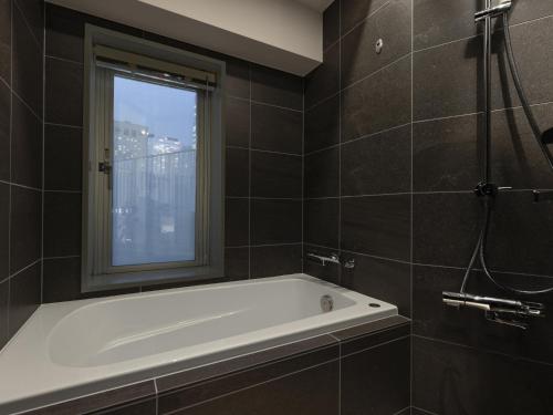 La salle de bains est pourvue d'une baignoire et d'une fenêtre. dans l'établissement Tokyu Stay Nishi Shinjuku, à Tokyo