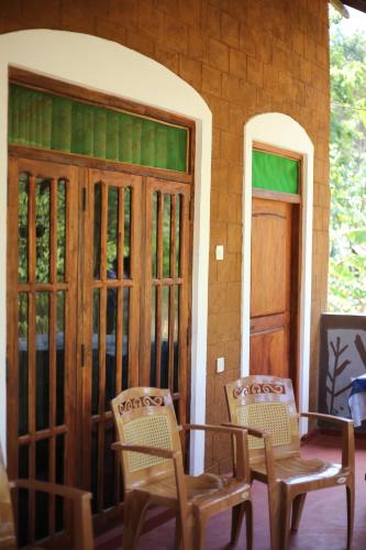 a patio with two chairs and a table and a door at Sigiriya Chena Villa in Sigiriya