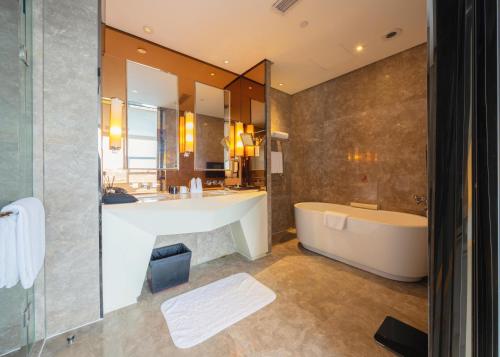 uma casa de banho com uma banheira e um espelho grande em Tonino Lamborghini Hotel Kunshan City Center em Kunshan
