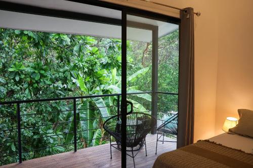 a bedroom with a balcony with a view of a jungle at Vista Verde Surf & Studios - jungle View in Carmen
