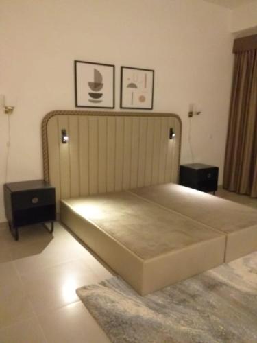 1 cama en una habitación con 2 mesas y 2 fotografías en Address marassi resort, en El Alamein