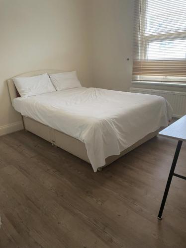 uma cama com lençóis brancos e almofadas num quarto em NKY CRYSTAL 4 Bed House Apartment em Londres