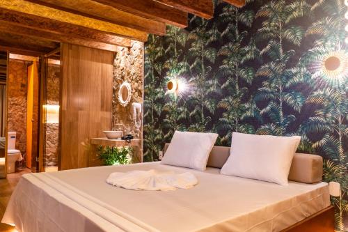阿拉亞爾達茹達的住宿－Sensações Suítes，一间卧室配有一张白色床和热带壁纸