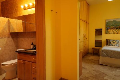 a bathroom with a sink and a toilet and a bed at Quinta Estrella in Valle de Guadalupe
