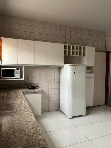 eine Küche mit weißen Schränken und einem Kühlschrank in der Unterkunft Ampla Casa Duplex com 4 suítes in Teresina