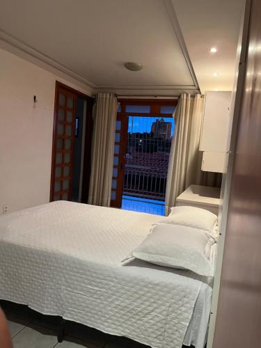 a bedroom with a white bed and a window at Ampla Casa Duplex com 4 suítes in Teresina