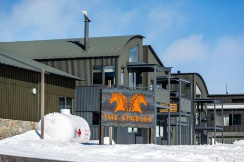 a building with a sign in the snow in front of it at Studio 2 - The Stables Perisher in Perisher Valley