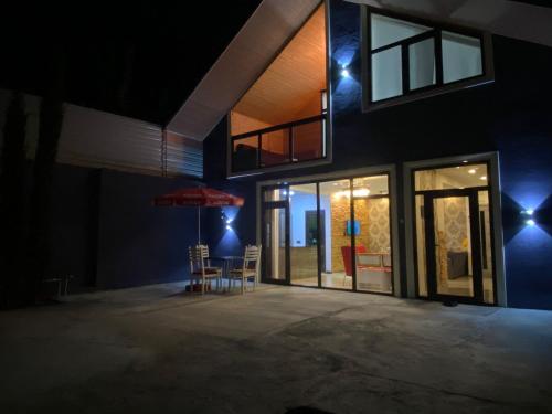 Cette maison dispose d'une terrasse avec des chaises et un parasol. dans l'établissement Sheki Guest Villa, à Shaki