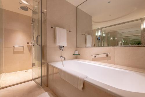 ein Bad mit einer Badewanne, einer Dusche und einem Spiegel in der Unterkunft Renaissance Suzhou Hotel in Suzhou