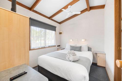 um quarto com uma grande cama branca e uma janela em Eureka Stockade Holiday Park em Ballarat