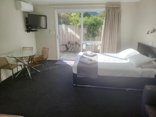 a bedroom with a bed and a table and a window at Ferrylink Motel in Picton