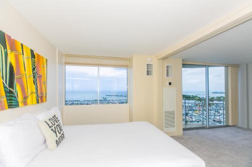 um quarto branco com uma cama grande e janelas grandes em Ilikai Marina 1386 em Honolulu