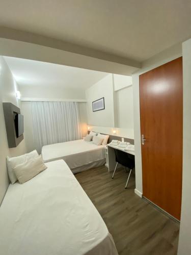 a hotel room with two beds and a desk at IT's Hotel in Caratinga