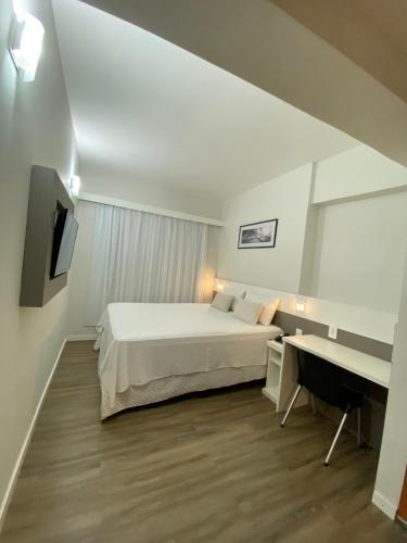 a bedroom with a bed and a desk and a television at IT's Hotel in Caratinga
