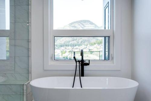 Luxury Golf Stay w/Hot Tub في كيلونا: حوض استحمام أبيض في حمام مع نافذة