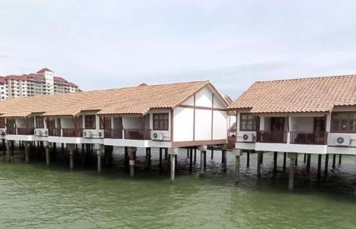 a row of houses on a pier in the water at Cuti-cuti port dickson water chalet in Port Dickson