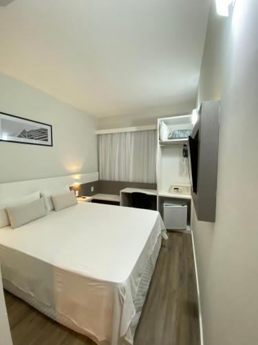 a bedroom with a white bed and a tv at IT's Hotel in Caratinga