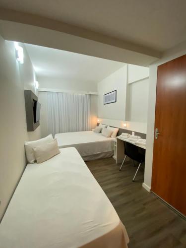 a hotel room with two beds and a desk at IT's Hotel in Caratinga