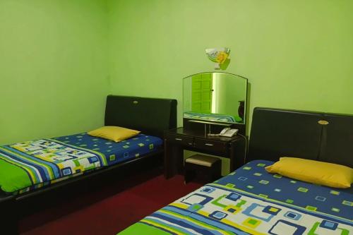 a small room with two beds and a mirror at Hotel Antik in Soreang