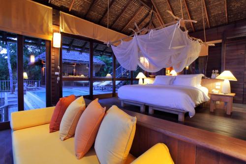 a bedroom with two beds and a couch at Six Senses Yao Noi in Ko Yao Noi