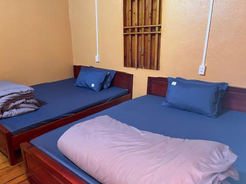 2 camas individuales en una habitación con almohadas azules en Hương Đồng Homestay, en Dồng Văn