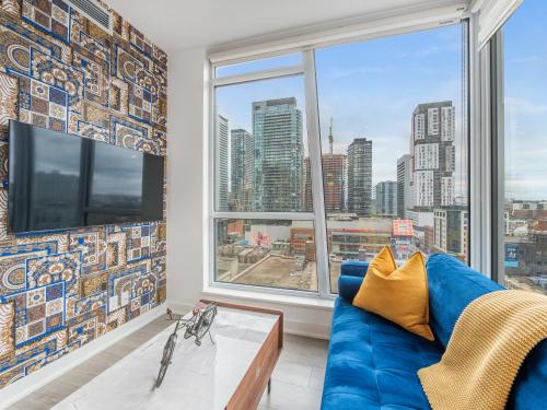 a living room with a blue couch and a large window at Boutique Vista Two Bedroom Suite - Toronto's Entertainment District in Toronto