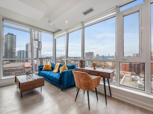a living room with a blue couch and large windows at Boutique Vista Two Bedroom Suite - Toronto's Entertainment District in Toronto